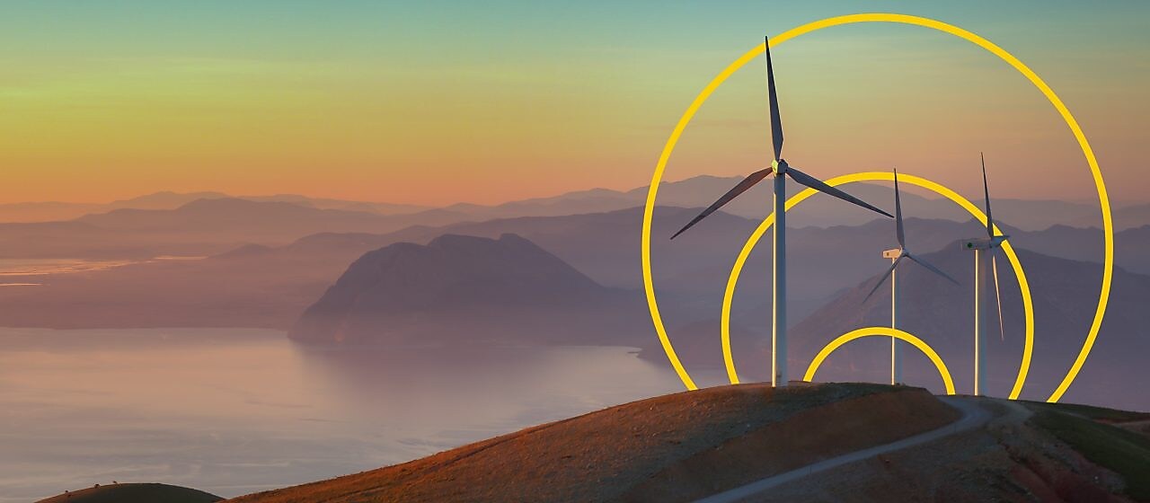 Фото трьох вітряних турбін на пагорбі з графічним зображенням «Досягнення нульових викиди»