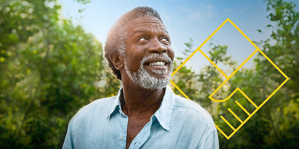 Бородатий чоловік посміхається на тлі дерев і графічного зображення «Створення цінності для акціонерів»