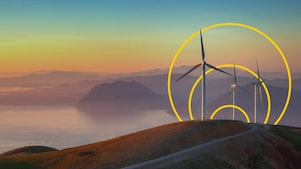 Фото трьох вітряних турбін на пагорбі з графічним зображенням «Досягнення нульових викиди»