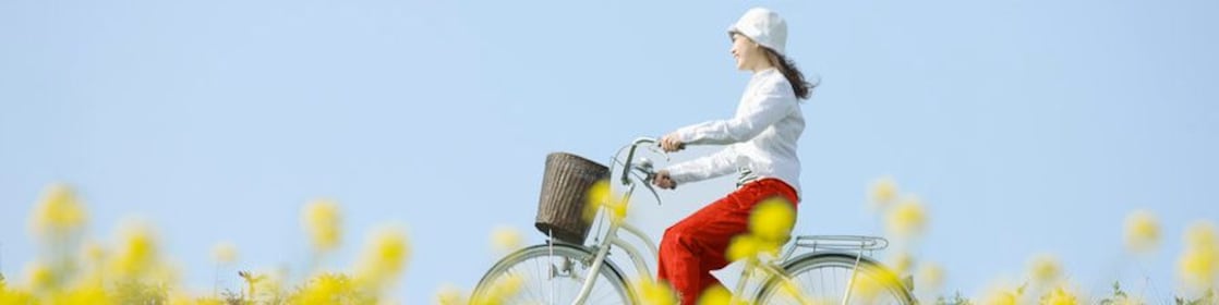 Молода жінка їде на велосипеді через заквітчане поле влітку