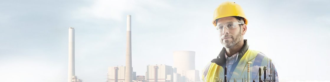 робітник у жовтій касці на тлі електростанції