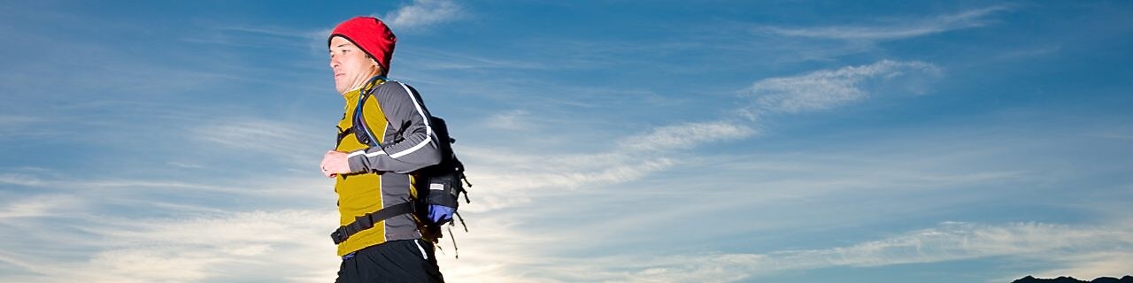 man with prosthetic leg, in running clothes, running in the hills in the early morning