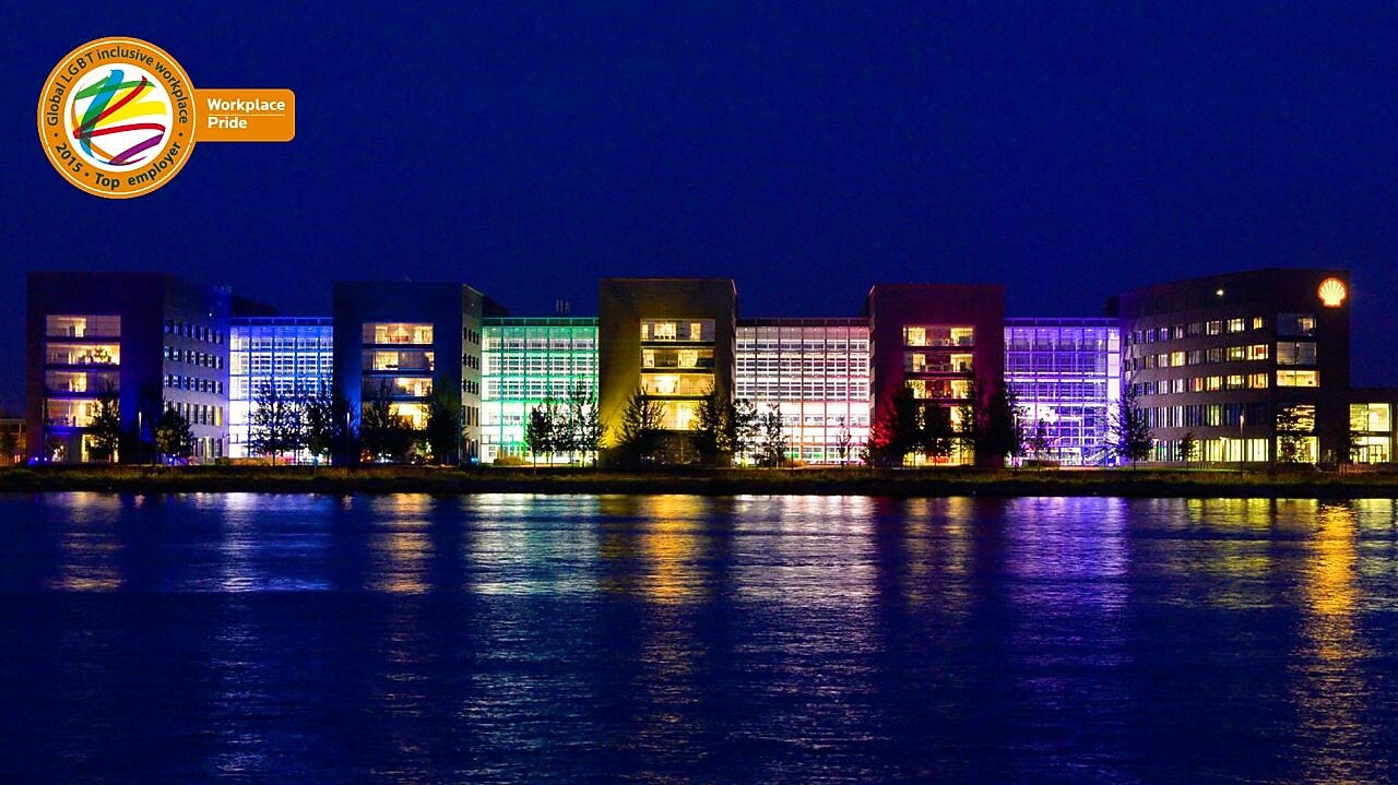 A set of lit office buildings reflect off the water at night