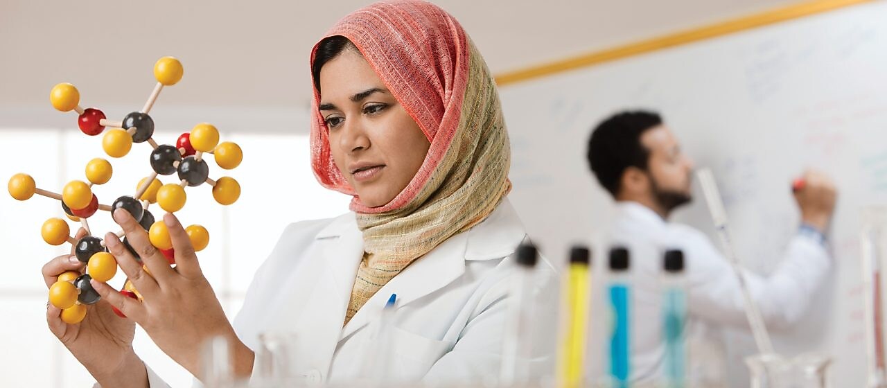 Молода жінка-науковець вивчає молекулярну модель