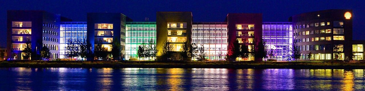 A set of lit office buildings reflect off the water at night