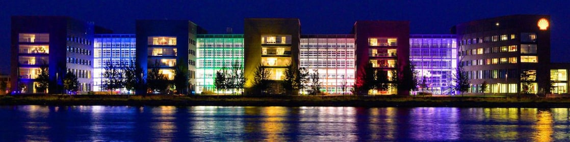 A set of lit office buildings reflect off the water at night