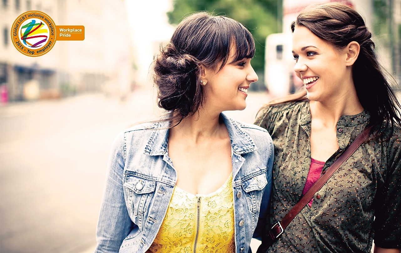 Two girls smile at each other as they walk down the street