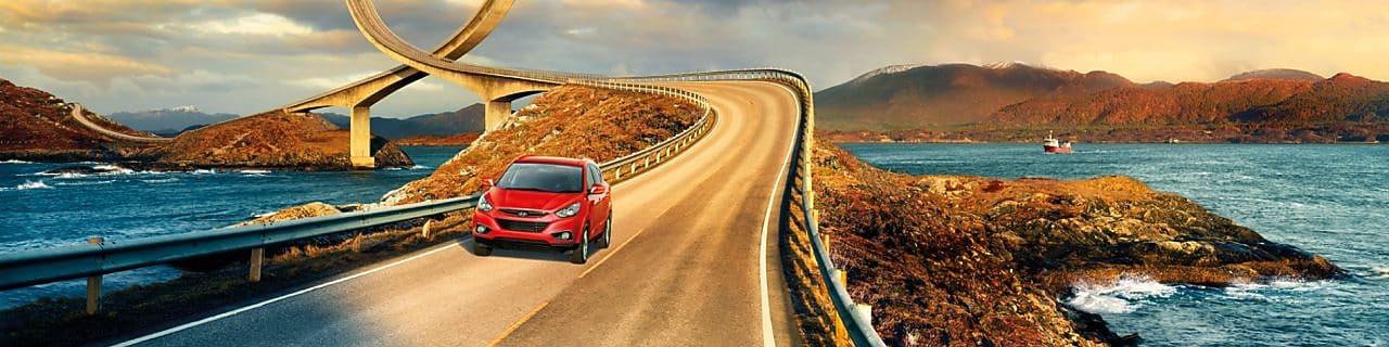 Red car driving on the road by the river