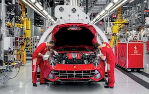 Червоний Ferrari стоїть на заправному терміналі станції «Шелл», чоловік спирається ліктем на заправну колонку